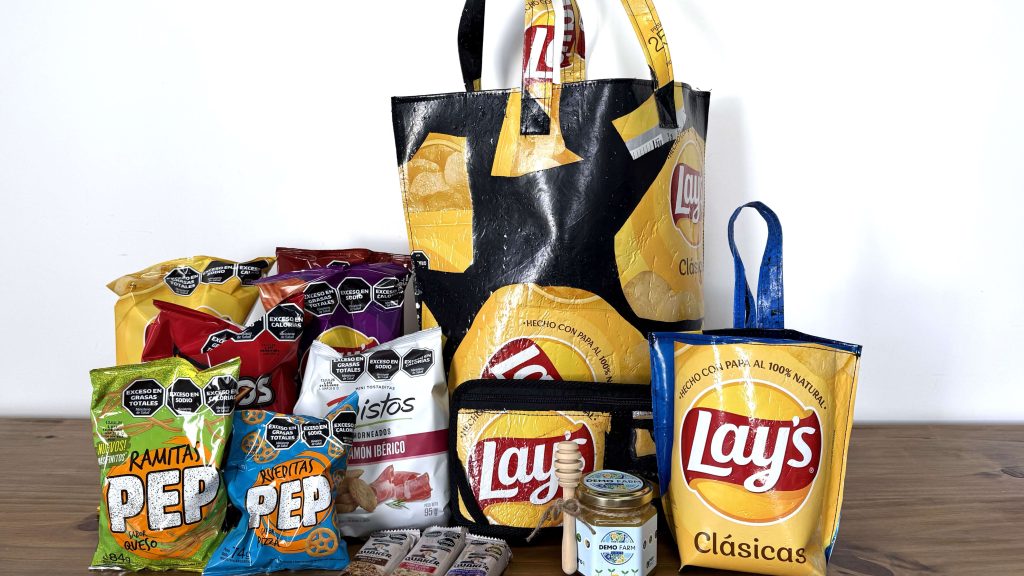 Paquetes de snacks, un frasco de miel y accesorios realizados con materiales reciclados